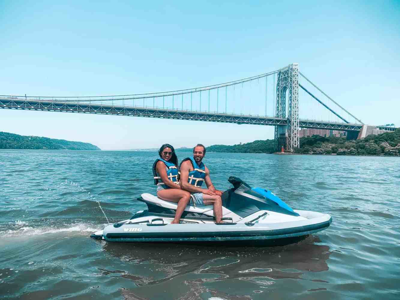 couple on a jet ski in the Hudson River in front of the Brooklyn bridge